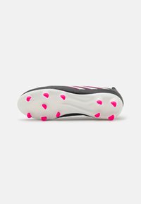 Zapatilla deportiva negra con parte superior texturizada, suela blanca y tachuelas rosas. Presenta un diseño elegante con acentos y rayas rosas en contraste.