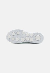 Semelle extérieure de chaussure de sport en caoutchouc blanc avec des pastilles rondes texturées et un motif rainuré pour une meilleure traction. Le design est minimaliste avec des bords lisses.