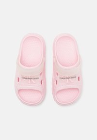 Pink rubber sandals with a textured surface, featuring a solid strap and speckled design. Displayed with "Calvin Klein Jeans" logo.