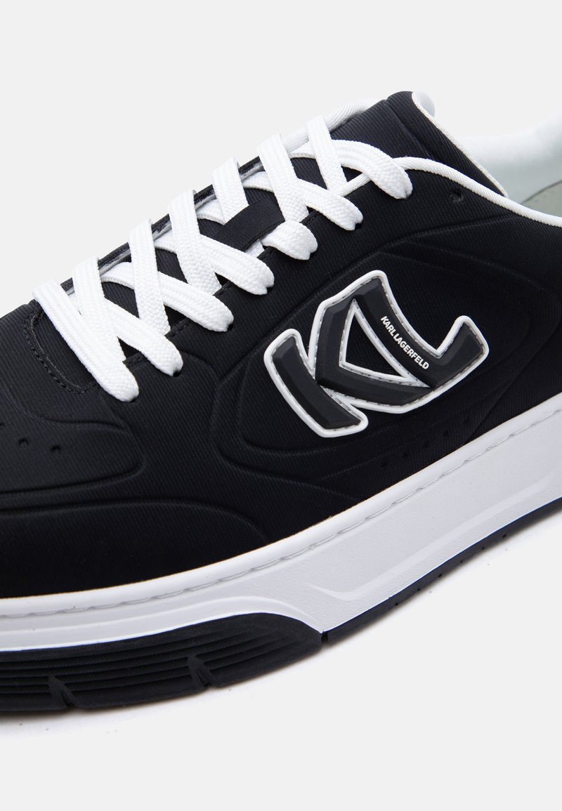 Zapatilla negra con cordones y suela blanca, con un logo "K" en relieve y el texto "Karl Lagerfeld" en el panel lateral.