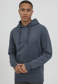 Donkerblauwe hoodie van zacht materiaal. Beschikt over een kangoeroezak, trekkoorden en ribgebreide manchetten. Eenvoudig, casual ontwerp zonder zichtbare logo's.