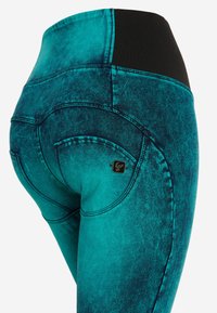 Leggings turchesi con una texture simile al denim, caratterizzati da una vita alta nera e dettagli di cucitura curvi sulle tasche.