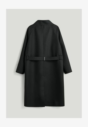 Sort lang frakke med bæltebagdetalje, lange ærmer og lige kant, vist bagfra mod en ensartet lys baggrund.
