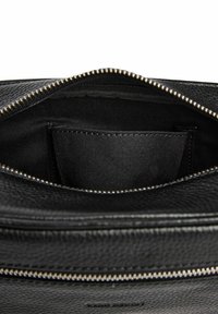 Zwarte leren handtas met een gestructureerde afwerking, ritssluiting en een binnenvak. Gevoerde binnenkant in donkere stof. Accenten van zilverkleurig beslag.