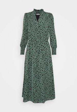 Groene midi-jurk met zwarte onregelmatige stippen, lange gebloemde mouwen, getailleerde taille en een hoge kraag met V-halsopening.