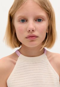Cream-colored knit halter top with a textured pattern and light purple straps, worn by a child with short blond hair and blue eyes.