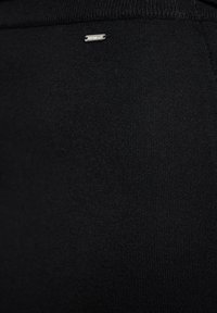 Schwarzer Stoff mit einer glatten Textur, der nahe der Oberkante eine kleine silberne Akzentuierung aufweist und ein enganliegendes Design bietet, das sich für Sportbekleidung eignet.
