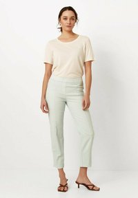 Lichtbeige t-shirt met korte mouwen, gecombineerd met mintgroene tapershorts met een elastische tailleband en horizontale stikdetails.