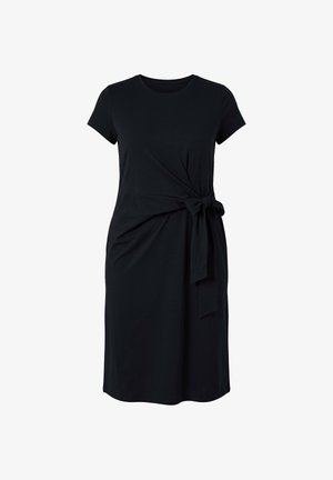 Abito nero al ginocchio con maniche corte e dettaglio con fiocco laterale in vita su sfondo semplice.