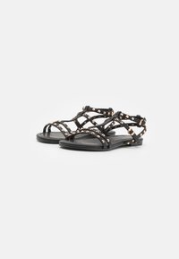 Svarta sandaler med flera remmar, med dekorativa rosaguld-nitar. Platt sula med minimalistisk design och justerbara spännen.