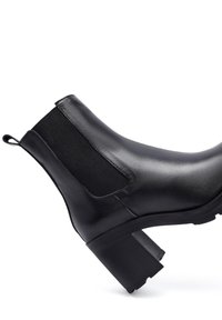 Stivale alla caviglia in pelle nera con pannelli laterali elastici, punta tondeggiante e tacco a blocco. Texture liscia e design minimalista senza adornamenti.