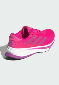 Baskets de sport rose vif avec une tige en maille, trois rayures en rose clair, semelle intermédiaire blanche avec un accent violet, design contour et lacets.