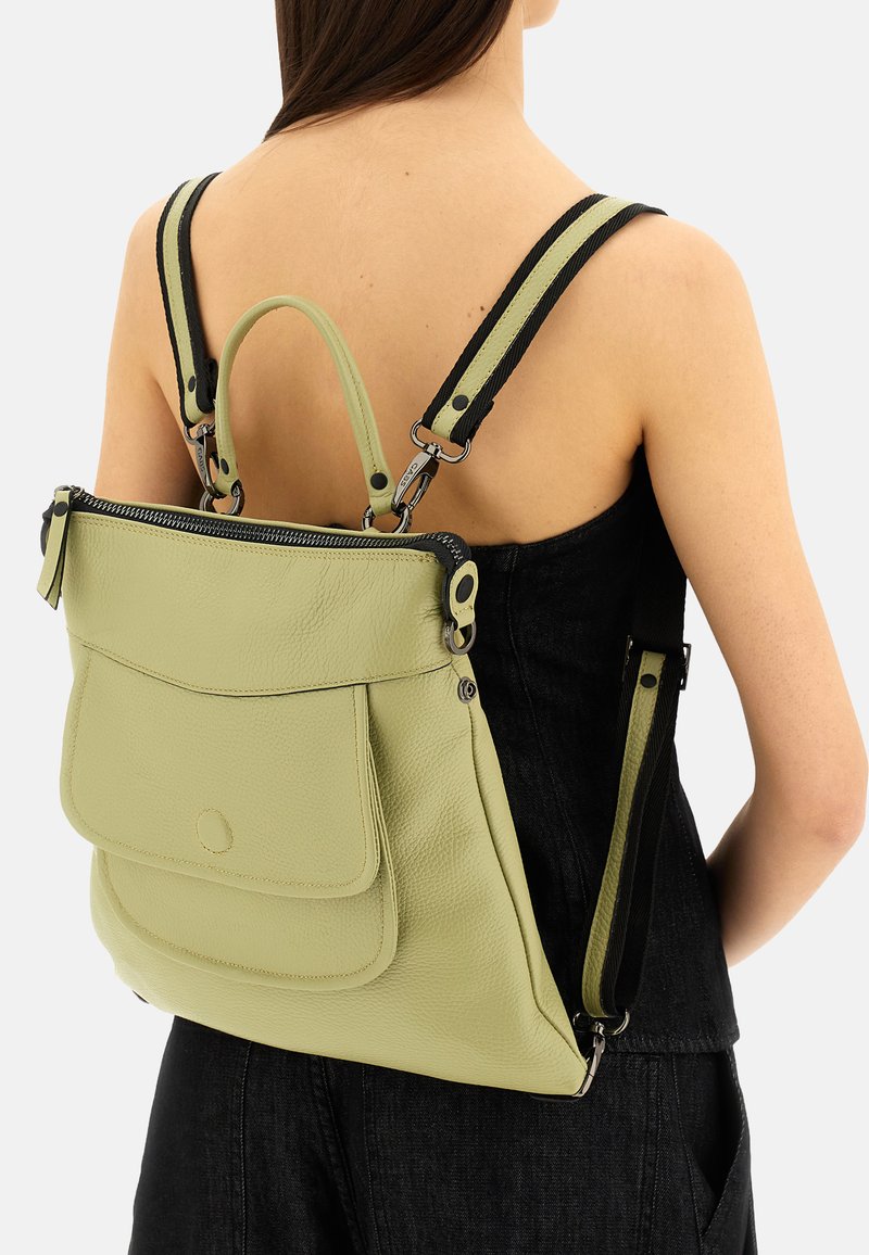 Zaino in pelle verde con finitura texturizzata, chiusura superiore con zip e spallacci neri regolabili, dotato di una tasca frontale e dettagli in metallo argentato.