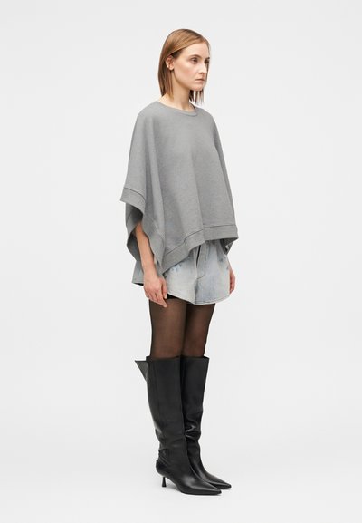 Sivi prevelik pončo z okrogelim izrezom, kombiniran s svetlo denim kratkimi hlačami in črnimi usnjenimi škornji s tkanima petami do kolen; prosojne črne nogavice.