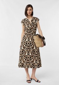 Ärmelloses, knielanges Kleid mit einem geometrischen Muster in Braun, Schwarz und Creme. Der Stoff ist leicht und hat einen elastischen Bund.