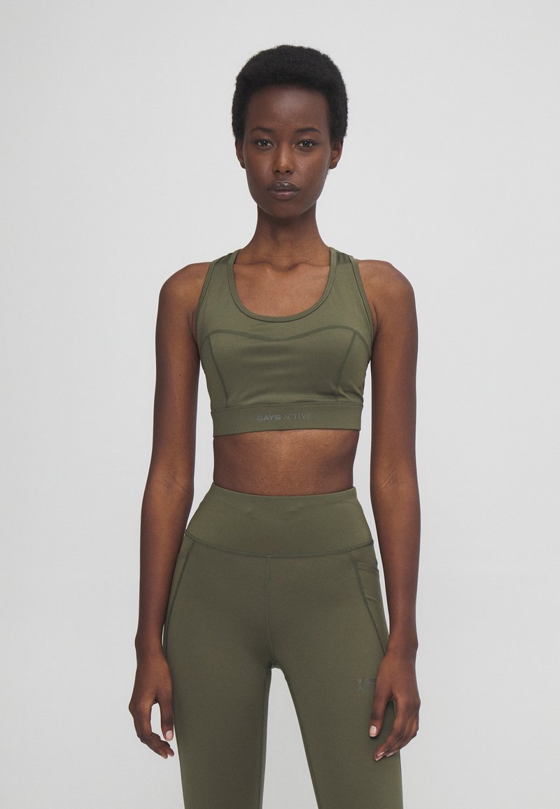 Olive green sports bra and matching high-waisted leggings made of stretch fabric. Features seamless design and subtle stitching details.