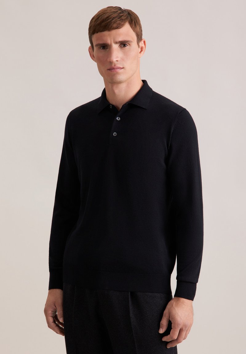 Schwarzes Langarm-Polo mit flachem Kragen, drei Knöpfen und gerippten Bündchen. Hergestellt aus einem weichen, strukturierten Stoff. Minimalistisches Design.