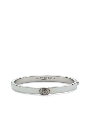 Srebrny, metalowy bransoletka z małym dekoracyjnym emblem i wygrawerowaną nazwą marki Kurt Geiger London wewnątrz.