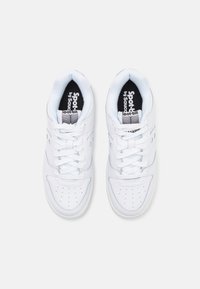 White athletic shoes with a smooth leather upper, round toe, perforated details, and flat laces. Interior features logoed fabric lining.