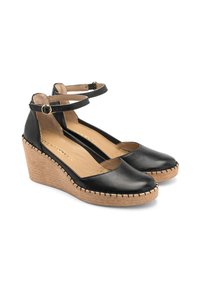 Scarpe col tacco a zeppa in pelle nera con cinturino alla caviglia, punta rotonda, base intrecciata simile al juta e dettaglio di cucitura lungo il bordo.