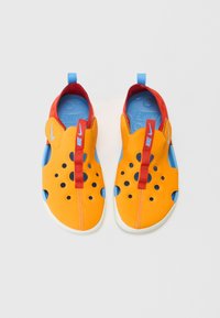 Des chaussures slip-on orange vif avec des accents rouges et une doublure bleue. Les caractéristiques comprennent des perforations pour la ventilation et des languettes de talon à boucle.