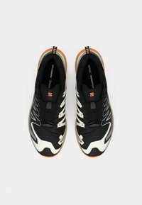 Pair of black, white, and orange Salomon athletic shoes with quick-lace system, viewed from above on a plain light background.