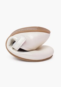 Zapatos de bebé de cuero suave en blanco con suela flexible, puntera redondeada y una cinta de Velcro para ponerlos fácilmente. Suela de goma texturizada.