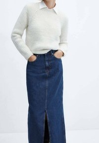 Valkoinen, kuvioitu neulepaita, jossa on resorit hihansuissa, yhdistetty siniseen farkkumaxi-hameeseen, jossa on etuhalkio ja klassinen viiden taskun malli.