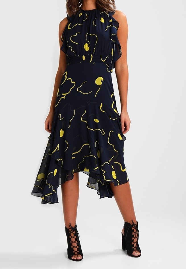 Laivaston sininen mekko keltaisilla abstrakteilla kuvioilla, röyhelökaula-aukko ja epäsymmetrinen helma. Yhdistetty mustiin nyörijalkineisiin. Kevyt kangas.