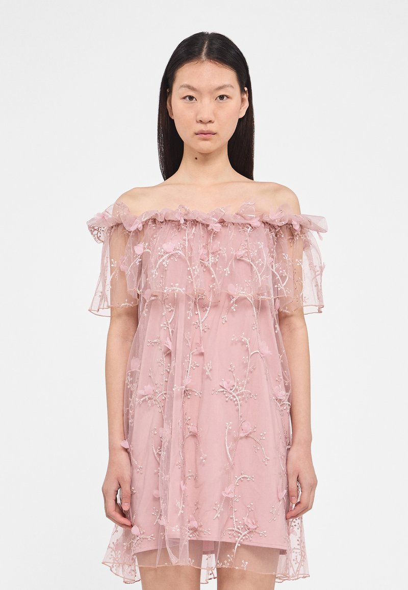Roze off-shoulder jurk van doorschijnende stof met geborduurde bloemmotieven en gerimpelde accenten rond de halslijn en mouwen.