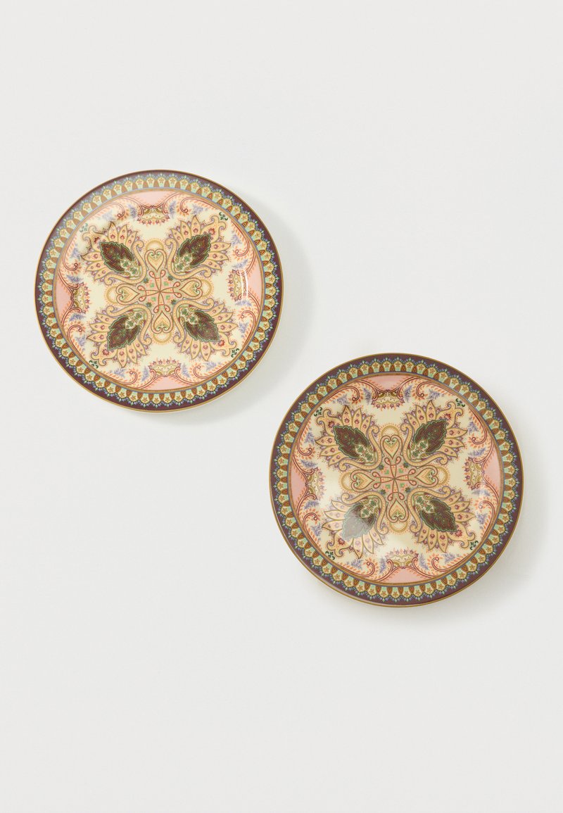 Deux assiettes décoratives rondes avec des motifs floraux et de feuilles symétriques élaborés en vert, rose, or et marron sur fond crème.