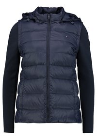 Péřová vesta bez rukávů s kapucí v tmavě námořnické modři, s prošívanými částmi, předním zipem a žebrovanými rukávy jako svetr ve stejné barvě.