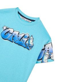 T-shirt in cotone turchese con stampa grafica della parola "CALI" in blu, accompagnata da bombolette spray. Collo rotondo e maniche corte.