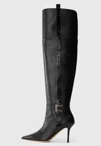 Black knee-high leather stiletto boot with pointed toe, vertical glossy stripe, and front metal buckle detail on plain light background.