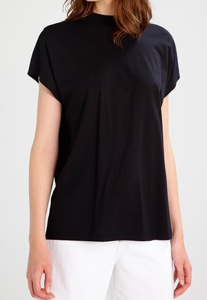 Black, short-sleeve top with a high neckline, made of soft fabric. Features a relaxed fit and smooth texture. Paired with white bottoms.