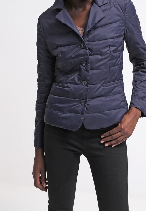 Marinblå kviltad jacka med snedkrage, dubbelknäppning och framfickor. Har en figursydd design och ett slätt, strukturerat material.