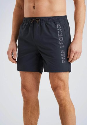 Donkerblauwe zwembroek met een elastische tailleband, een trekkoord en een zijzak. Kenmerkt zich door een horizontale grafische tekst langs de zijkant.
