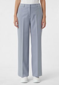 Jasnoszare szerokie spodnie wykonane z gładkiego materiału, o dopasowanym kroju, z przodu z krokami i płaskim paskiem w talii.
