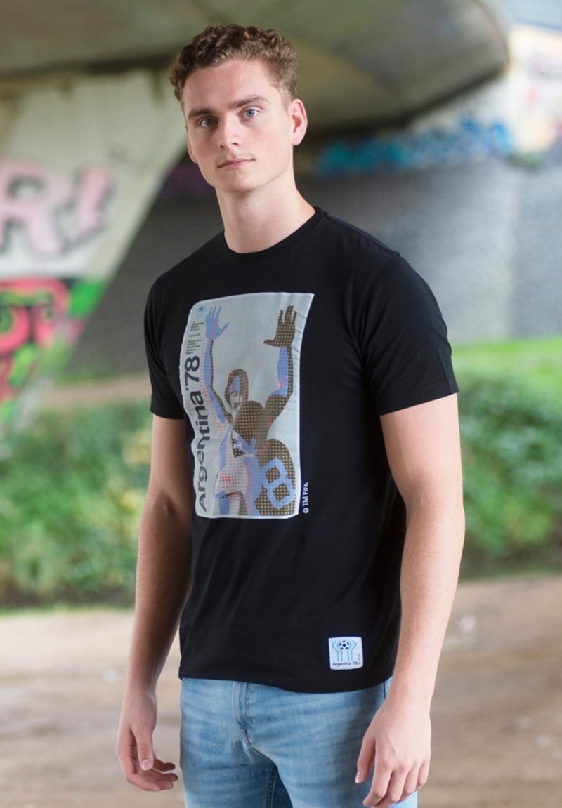 T-shirt nera con una stampa grafica di una figura con le mani aperte, accompagnata dal testo "Argentina 78" in un colore contrastante.