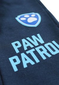Tissu bleu marine avec un logo en forme de bouclier bleu clair comportant une patte d'animal et le texte « PAW PATROL » en lettres bold bleu clair contrastantes.