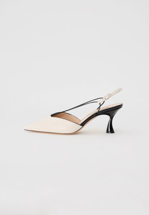 Beige syntetisk slingback sko med spids tå og sorte accenter samt en buet sort hæl. Har en tynd ankelrem til lukning.