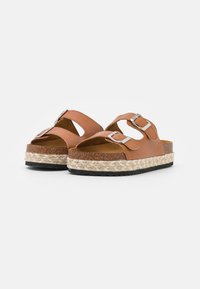 Bruine leren sandalen met twee verstelbare banden, espadrille-stijl jute zool en een rubberen loopzool voor grip. Plat ontwerp met open teen.