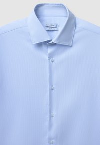 Hellblaues Slim-Fit-Hemd aus strukturiertem Stoff, mit durchgeknöpftem Vorderteil und klassischem Kragen, etikettiert mit "Calliope" und Größe L.