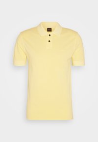 Polo pour homme à manches courtes de couleur jaune clair, avec col, deux boutons noirs et un logo "BOSS" discret sur la poitrine.