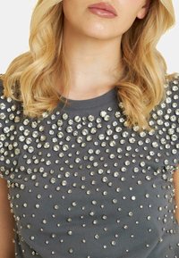 Gray short-sleeve top adorned with numerous shiny, clear gemstones arranged in a scattered pattern across the front. Smooth fabric texture.