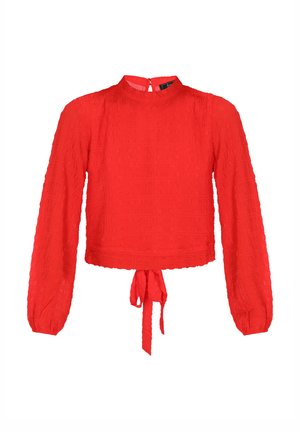 Blusa roja texturizada con mangas largas, escote redondo y un lazo en la cintura. Presenta un sutil patrón arrugado y cremallera en la parte posterior.