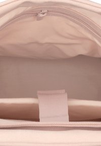 Világos rózsaszín anyagból készült tasak, tetején cipzáras záródással. Belseje sima tapintású, és egy kis textildivider található benne, amelyen egy hurkos heveder segíti a könnyű hozzáférést.