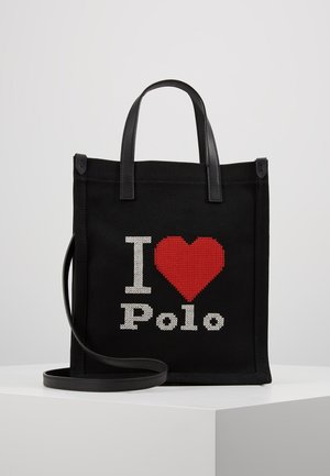 Sort mulepose med læderhåndtag og rem, med hvid tekst og et rødt hjertesymbol med teksten "I love Polo" foran.