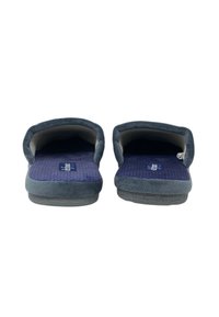 Pantofole in tessuto grigio con superficie liscia, parte posteriore aperta e soletta viola con texture. Presentano un design semplice e una suola grigia flessibile.