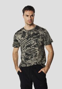 Short-sleeve, crew-neck t-shirt in olive green with black graphic patterns and text; features a small label on the front.